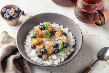 Rice porridge with banana, blueberries, chia seeds and honey sauce on a table, hot and healthy breakfast