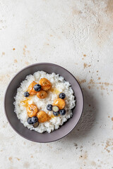 Rice porridge with banana, blueberries and honey sauce on a table isolated, hot and healthy breakfast. Top view