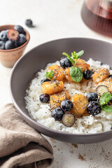 Rice porridge with banana, blueberries, chia seeds and honey sauce on a table close up, hot and healthy breakfast