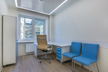 The office of an outpatient clinical facility, ready to receive patients. A table with an ergonomic chair.