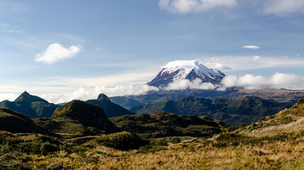 Fototapeta premium Volcán Antisana: Guardian of the Ecuadorian Highlands This stunning photograph showcases the Antisana Volcano, standing majestically above the rolling páramo landscape of Ecuador’s Andean highlands.