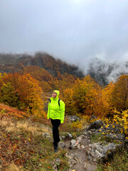 Woman standing and looking at landscape of autumn bright forest and mountains