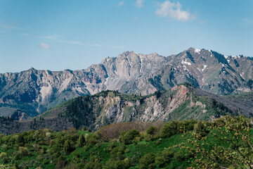 Naklejka premium Majestic mountain landscape of Kyrgyzstan showcasing lush greenery and rugged peaks under a clear blue sky