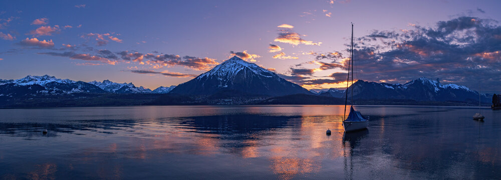 Splendid sunset over the Niesen Mountain (socalled Swiss Pyramid) with its shape reflection on Lake Thun - panorama