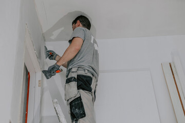 A young builder is plastering a doorway.