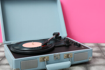 Obraz premium Record player with vinyl disk on table near pink wall