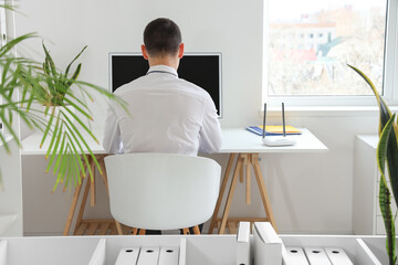 Businessman with wi-fi router working at table in office, back view