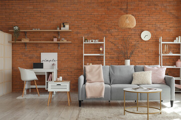 Interior of living room with sofa, workplace and willow branches in vase