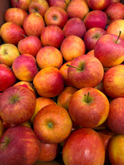 Fresh red and yellow apples piled together in a market display. Vibrant colors and natural textures highlight their ripeness and freshness.