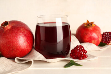 Glass of fresh pomegranate juice and fruits on white wooden table