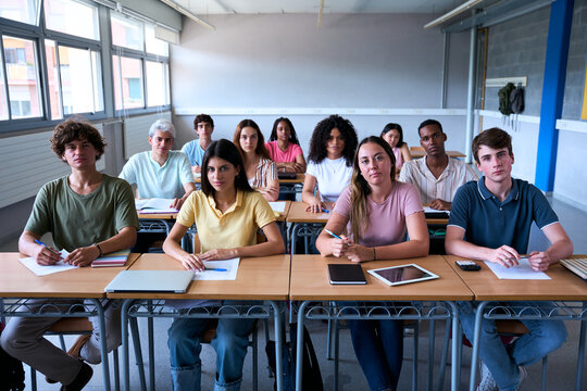 Confident group of university college sitting at classroom looking at camera with serious face. Portrait of Students of high school study together. People, education and community people