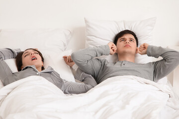 Young annoyed man suffering from loud snoring of his wife at home