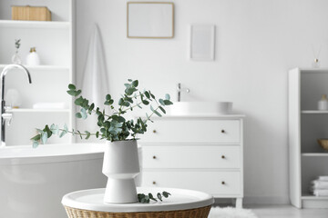 Vase with eucalyptus twigs on table in interior of bathroom