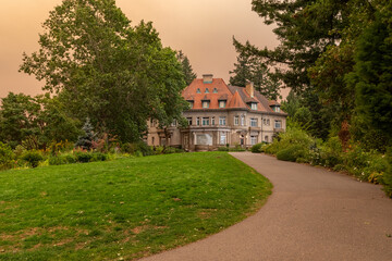 Fototapeta premium Pittock Mansion in Portland, Oregon, under an orange-tinted sky caused by thick wildfire smoke from the devastating 2020 fires, highlighting environmental disaster effects