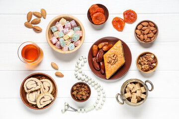Composition with different Eastern dishes, cup of tea and tasbih on white wooden background. Ramadan celebration