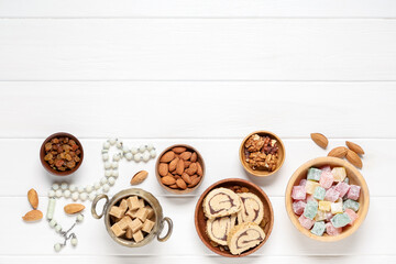 Composition with different Eastern dishes and tasbih on light wooden background. Ramadan celebration