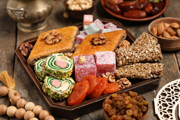 Board with delicious Eastern sweets for Ramadan celebration on wooden table