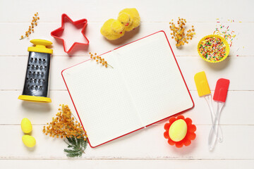 Composition with blank recipe book, baking tools and Easter decor on white wooden background