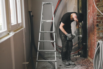 A young man prepares a puncher for breaking the wall.