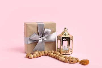 Fanoos, tasbih and gift box on pink background. Ramadan celebration