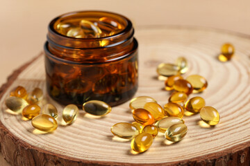 Wooden board with jar of fish oil capsules on color background, closeup