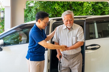 Asian man caregiver or taxi driver helping senior man patient get in the car to get to medical appointments or healthcare therapy sessions at hospital. Assisted elderly patient transportation services