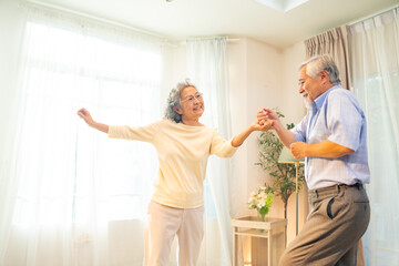 Fototapeta premium Happy Asian family senior couple enjoy and fun leisure activity lifestyle dancing together in living room. Healthy elderly husband and wife relaxing at home. Aged people mental healthcare concept.