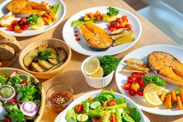 Salmon steak with organic vegetables salad and fried potato on dining table. Happy family enjoy...
