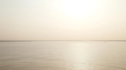 Calm sea at sunrise, hazy horizon.