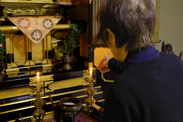 仏壇で供養をする高齢女性