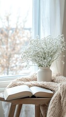 Cozy winter home interior with an open book, knitted blanket, and gypsophila bouquet by window