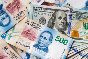 Macro close-up of 500 Mexican Pesos and 100 Dollar bills mixed up