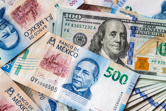 Macro close-up of 500 Mexican Pesos and 100 Dollar bills mixed up