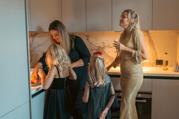 Family Kitchen Party Halloween: Women and girls prepare snacks in modern kitchen during a festive Halloween gathering.