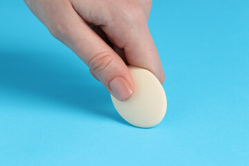 Woman using eraser on light blue background, closeup