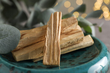 Palo santo sticks and eucalyptus leaves on table, closeup