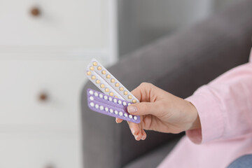 Woman with blisters of contraceptive pills indoors, closeup