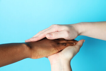 Stop racism. People of different skin colors holding hands on light blue background, closeup
