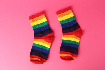 Pair of socks in LGBT colors on pink background, flat lay