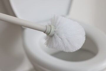 Toilet brush and bowl indoors, selective focus