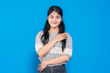 Young Asian woman with long black hair gently smiling and hands on her chest, expressing gratitude...