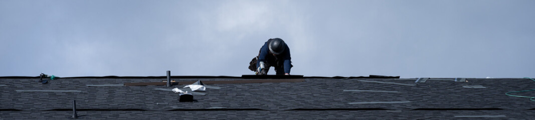New home construction site, roofing contractor (workman labor) putting down asphalt shingles,...