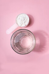 A glass of water with a scoop of dietary supplements for athletes, representing sports nutrition, hydration, and fitness support on a clean and minimal background.