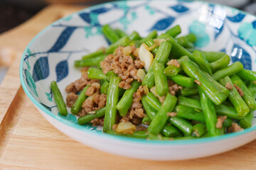 Stir-fried minced pork with green beans, Asian homemade food, close-up Thai-Chinese food image with natural light in the kitchen.