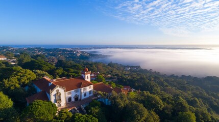 Fototapeta premium Panoramic view of a historical building nestled in a lush landscape, surrounded by fog