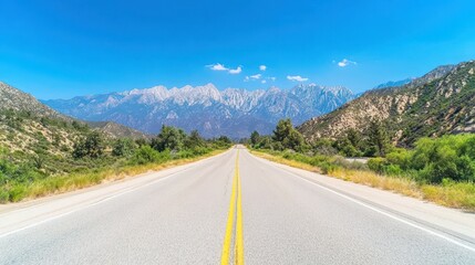 Fototapeta premium Endless Highway to the Mountains: A long, straight highway stretches towards majestic mountain range under a bright blue sky. Capture the sense of adventure and vastness of the open road