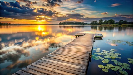 Obraz premium Serene Sunset Vista Wooden Dock Extending into Calm Waters Reflecting Colorful Sky and Aquatic Plants