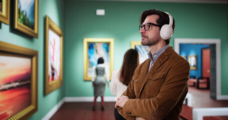 young man with headphones walks through a museum gallery viewing ancient