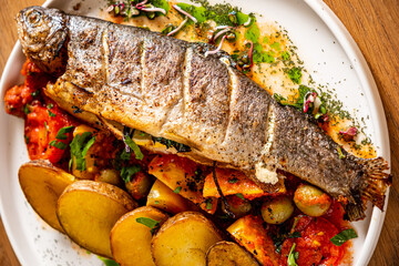 Freshly grilled fish served on a plate with colorful vegetables and seasoned potatoes