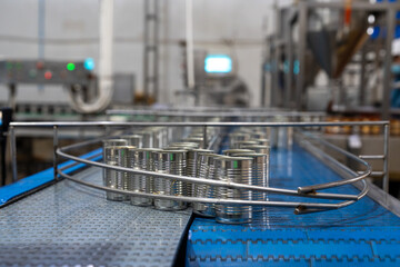 Canned food manufacturing process, metal cans moving along a conveyor belt while being filled....